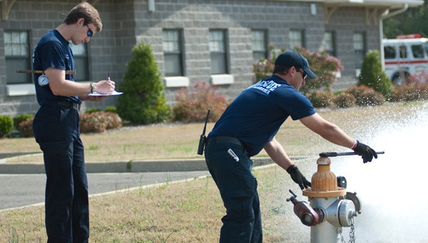 Firefighters Forrest Harvey and Sam Curtis test the fire hydrant in front of Station 3 on Highway 80 East.