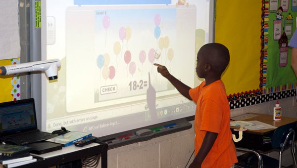 Za'varis Knott uses the interactive whiteboard in Amanda Meadows' class at Westside Elementary. Demopolis Middle School and Demopolis High School will be receiving these boards over the summer as part of a system-wide technology upgrade.