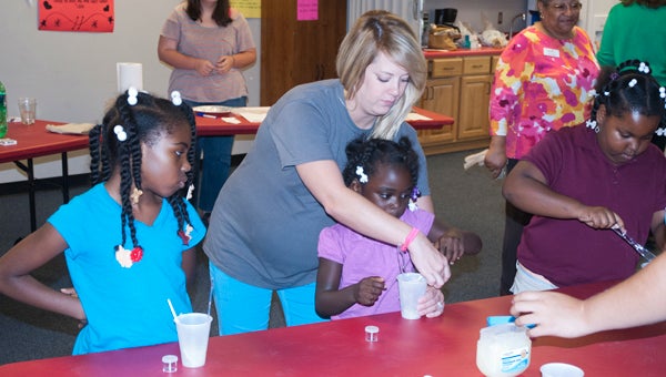 Cortnie Draper, Girl Scouts Pathway Program manager, helps Joy Gay, Amber Marsh and Rebecca Hinton make lip gloss during STEM Day on Monday at the Theo Ratliff Center.