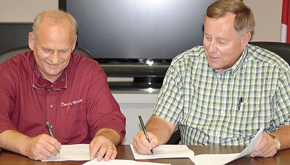 Dave Oliver of Dave’s Market, right, and Thomaston Mayor Jeff Laduron sign an agreement that will bring a grocery store to the town in the near future. A grocery store has been a goal for Thomaston and Marengo County officials for many years.