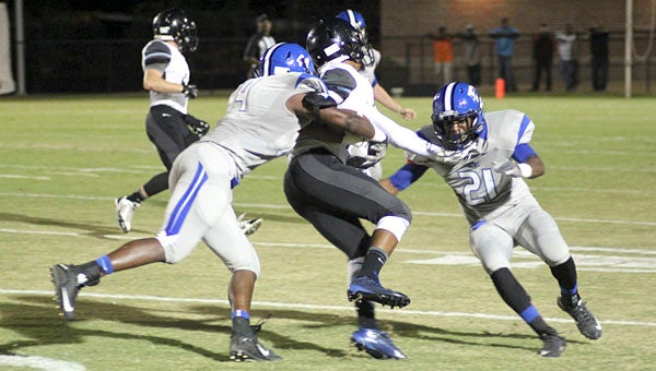 Rahmeel Cook (44) and A.J. Collier (21) close in on a Helena ball carrier.