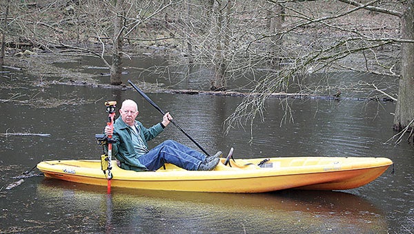Marengo County Commissioner Dan England surveys property from a kayak on a pond along Gandy Ferry Road in Demopolis. The county commissioner, who owns a survey company, is doing the work at no charge to the county.